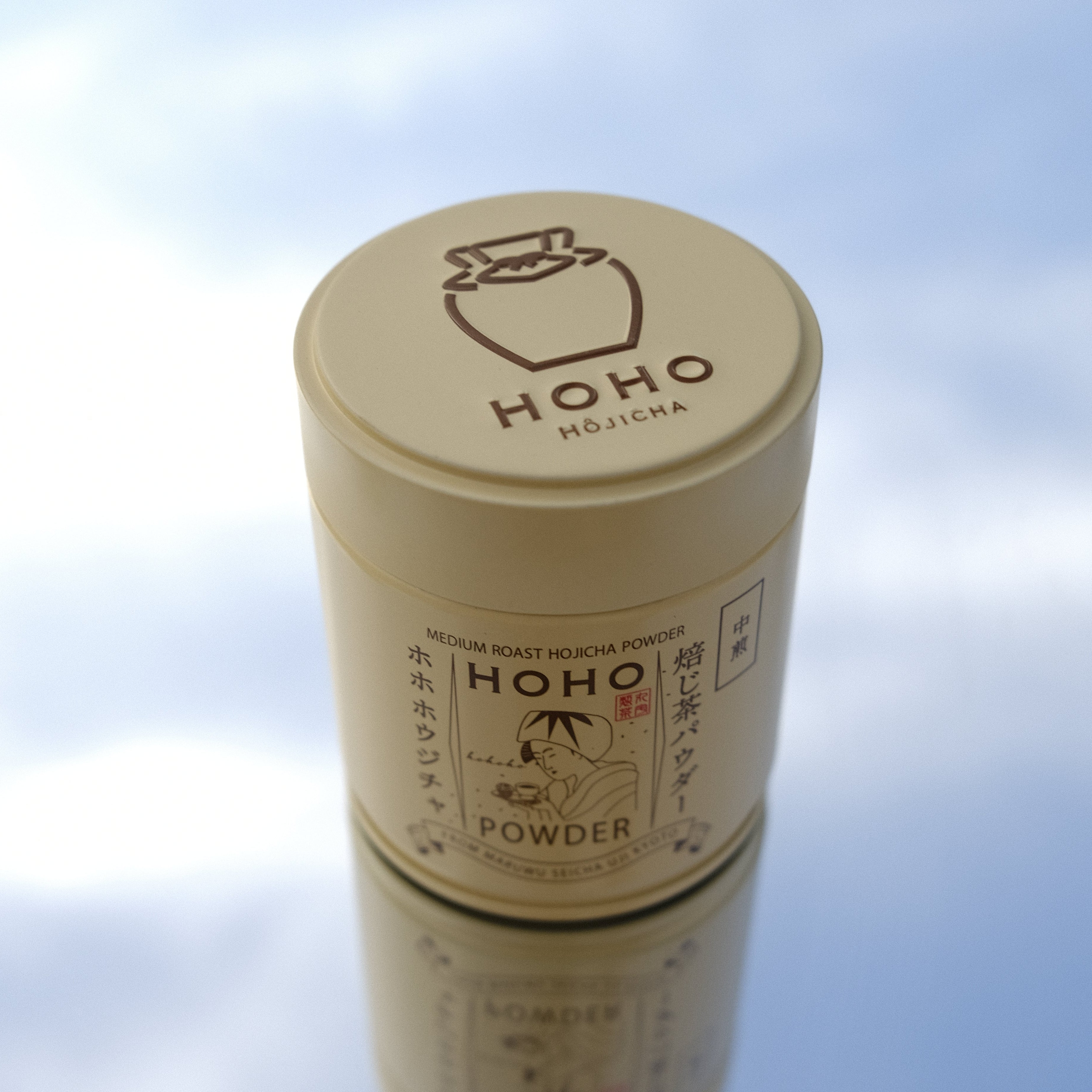  cylindrical product with 'HOHO' branding against a blurred blue sky background