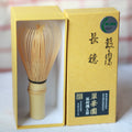 Traditional Japanese tea whisk with a yellow box on a white background