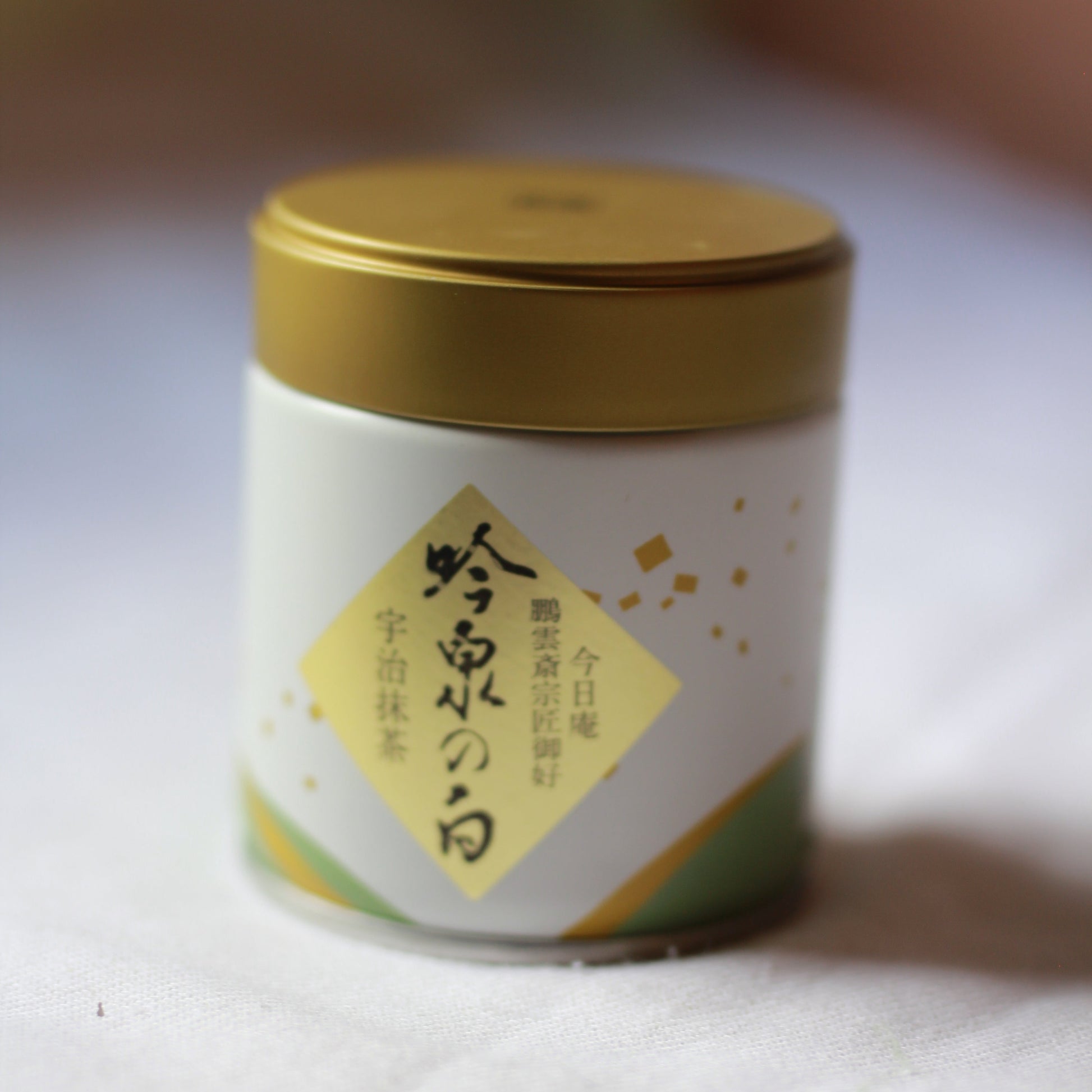 Small cylindrical container with a gold lid on a white background